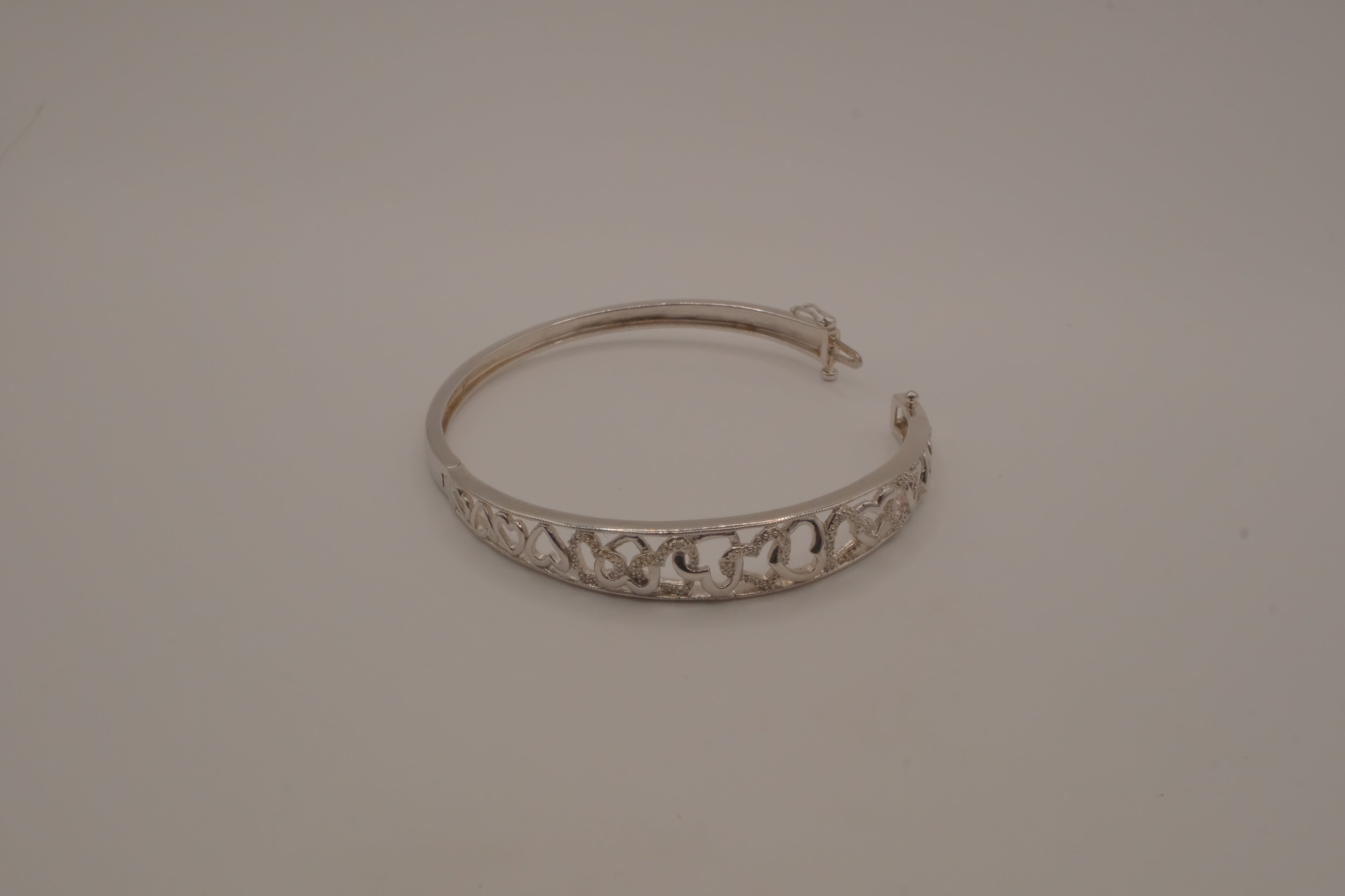 Sterling silver interlocking heart pattern hinged bangle bracelet