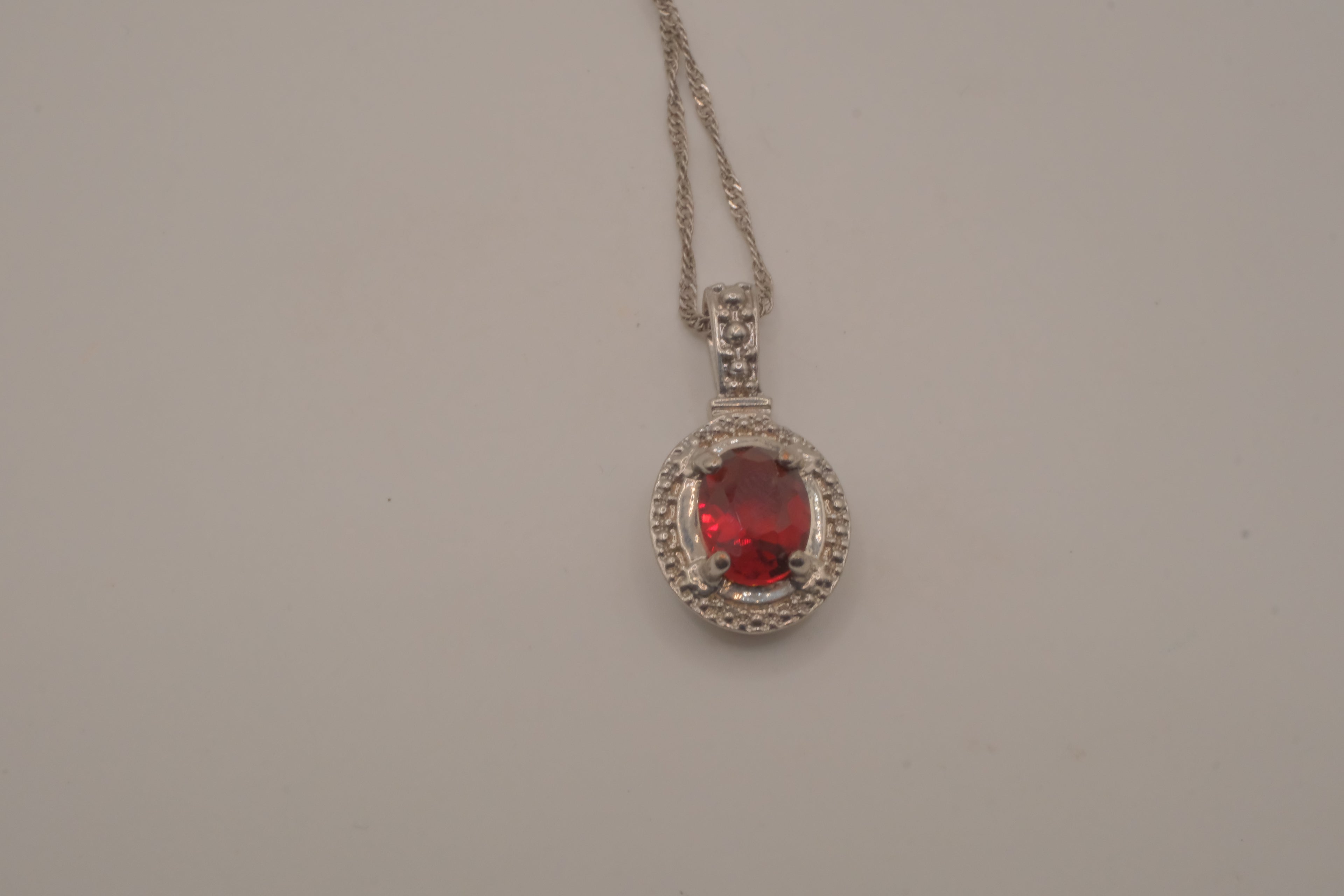 Oval-cut red gemstone halo pendant necklace