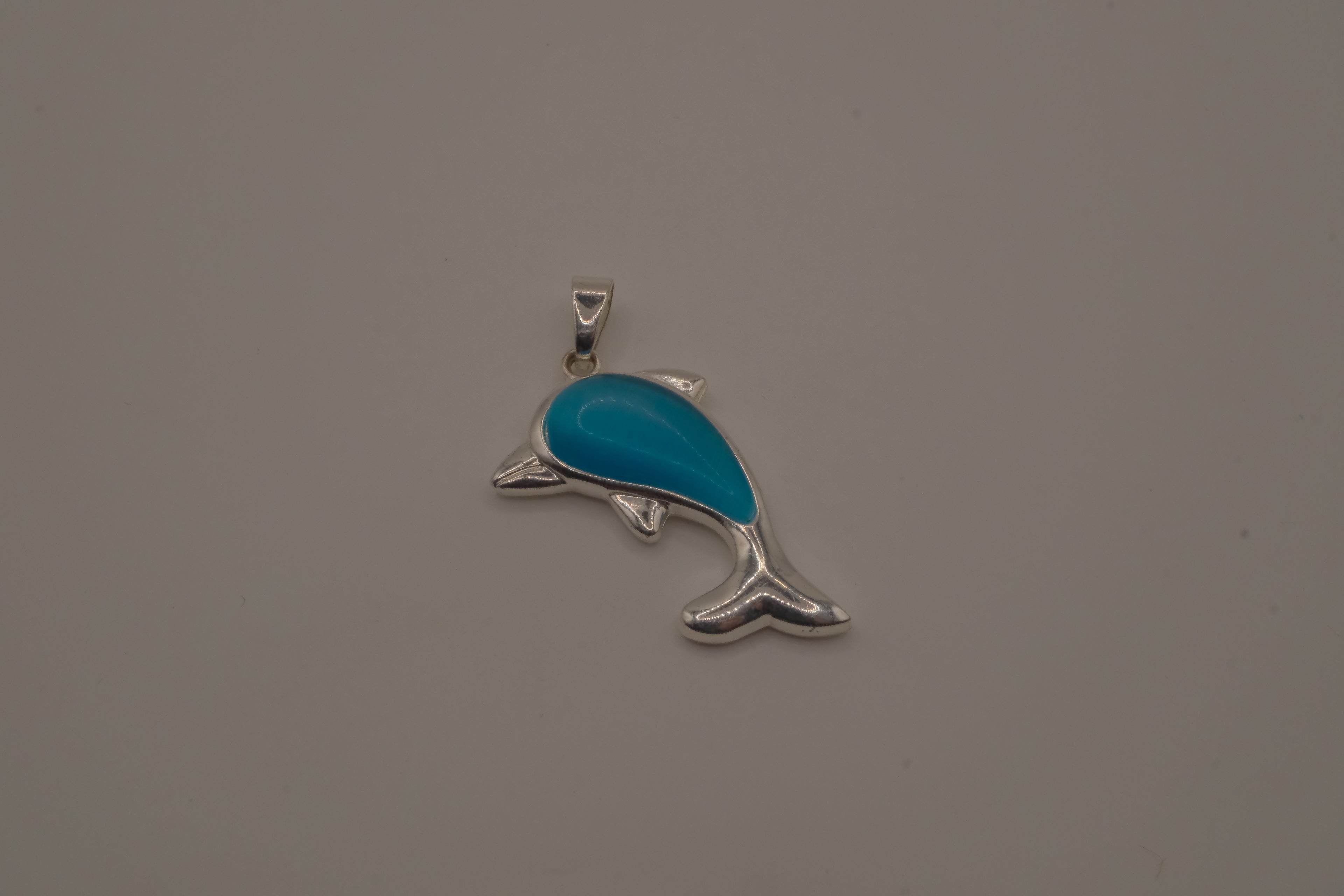Dolphin pendant inlaid with a blue cabochon