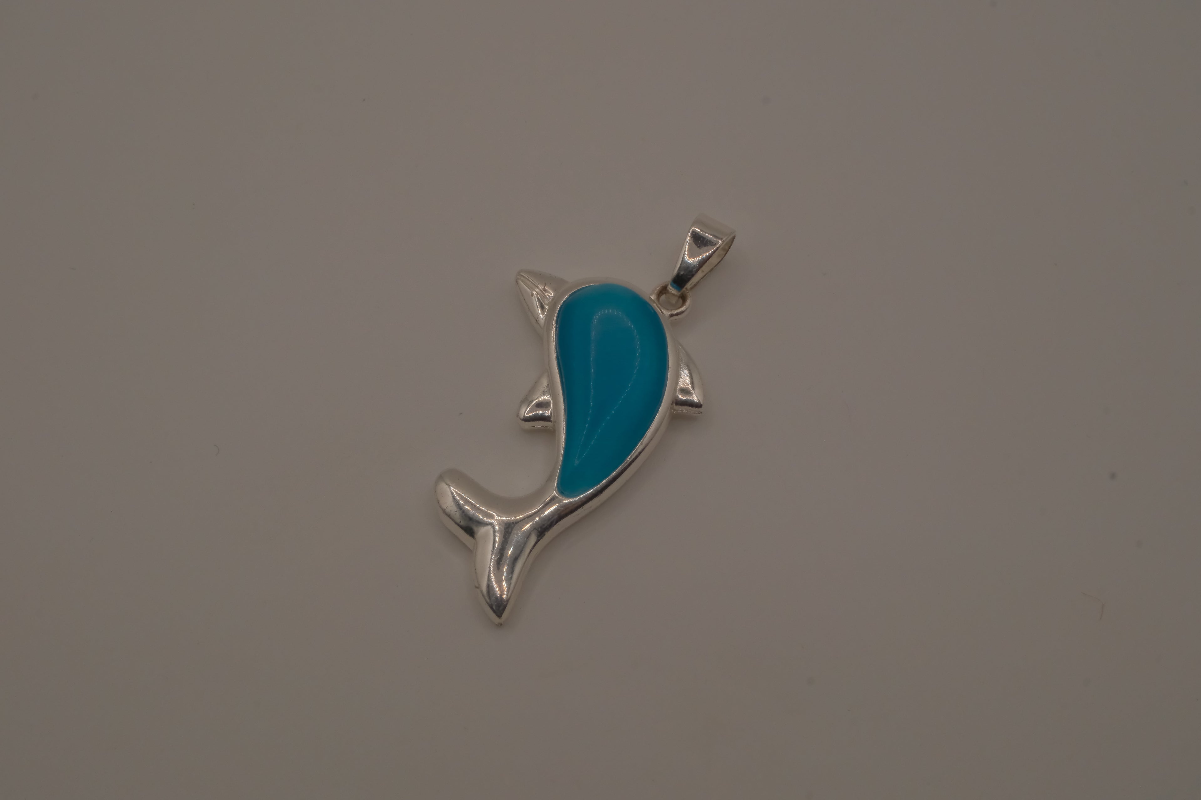 Dolphin pendant inlaid with a blue cabochon