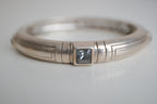 Silver toned patterned bangle with square grey stones