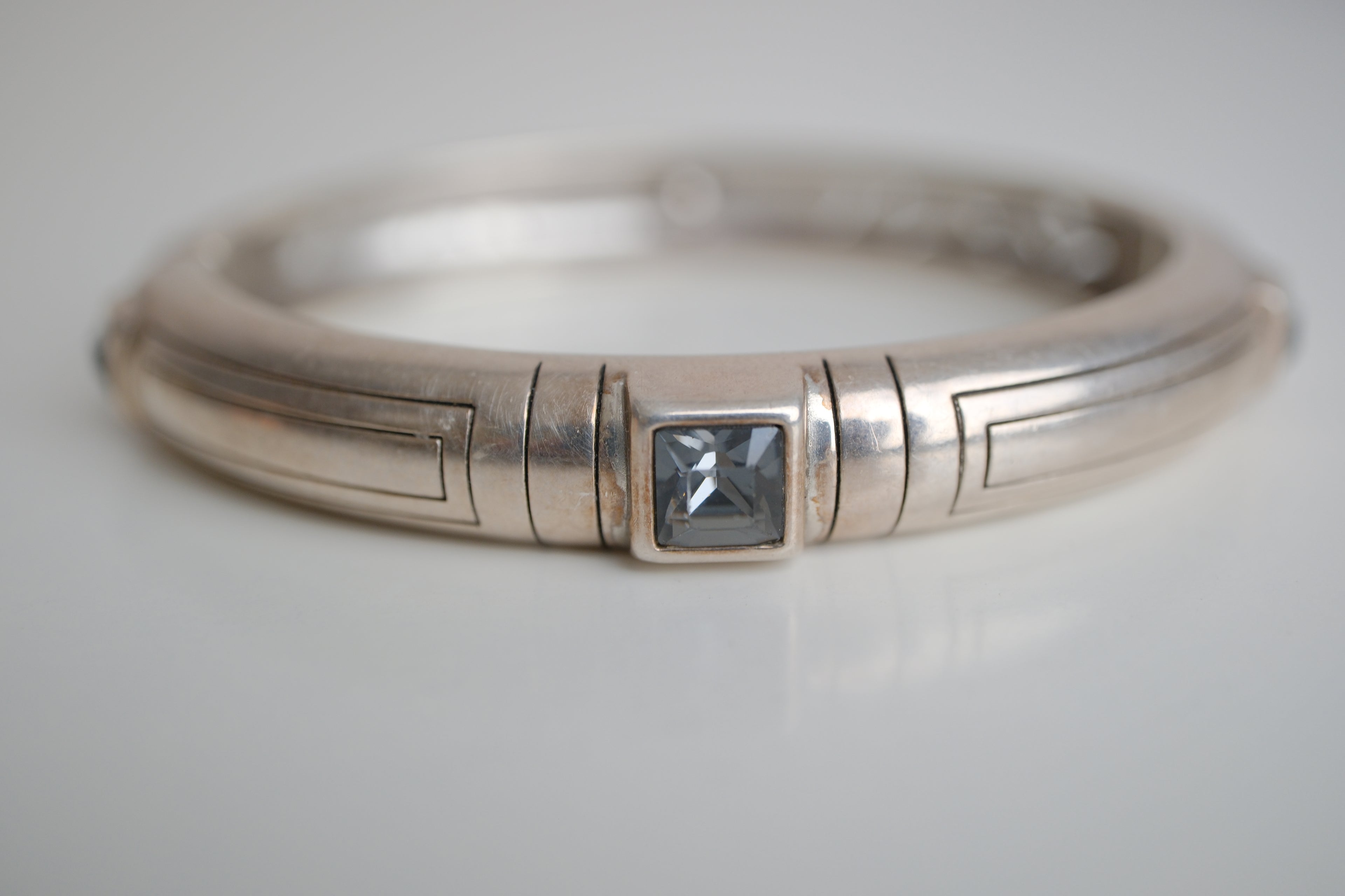 Silver toned patterned bangle with square grey stones