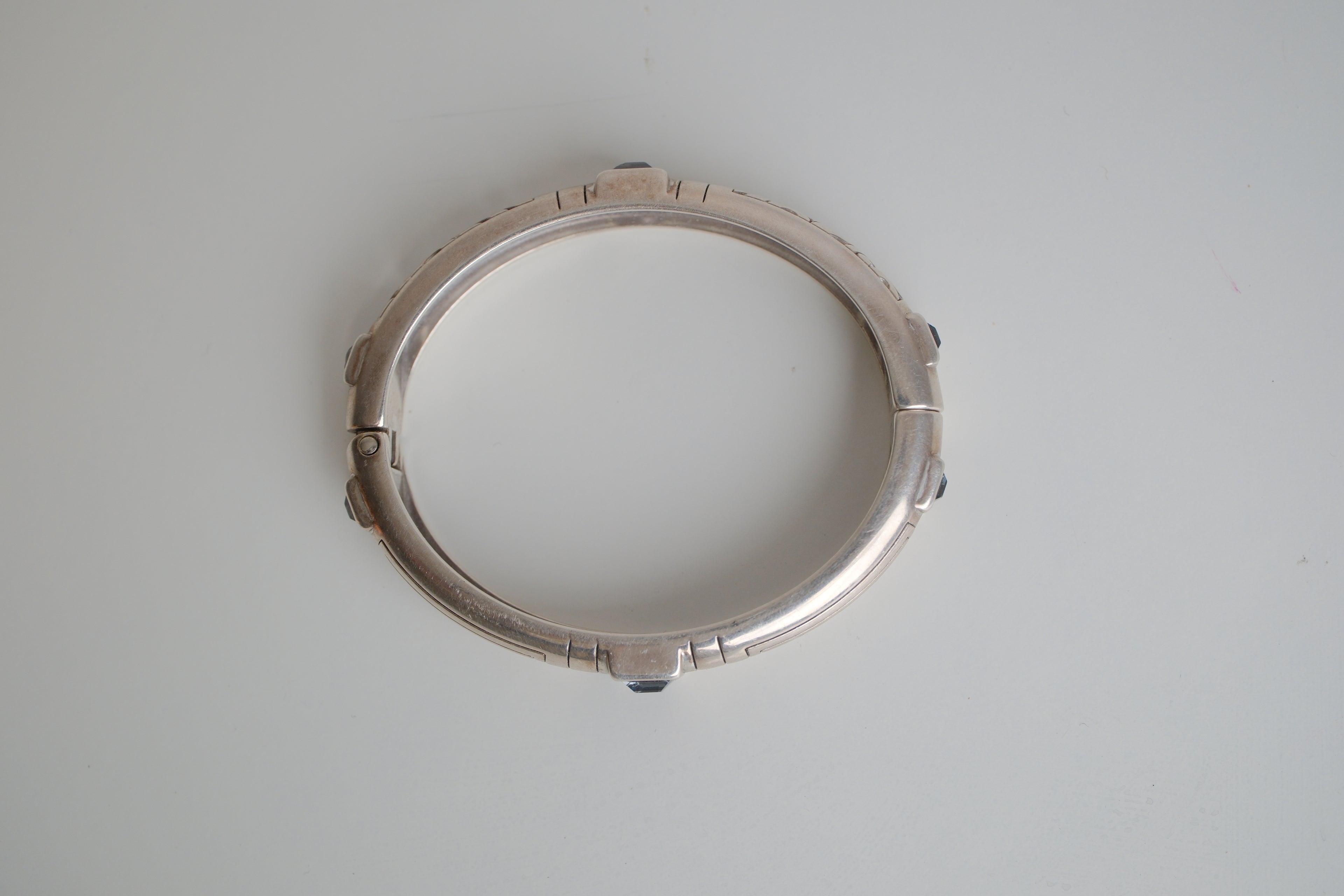 Silver toned patterned bangle with square grey stones