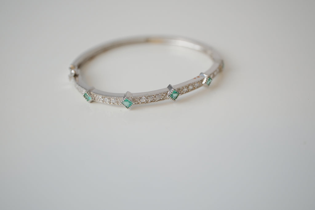 Silver tone bangle bracelet with white and green stones