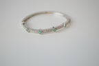 Silver tone bangle bracelet with white and green stones