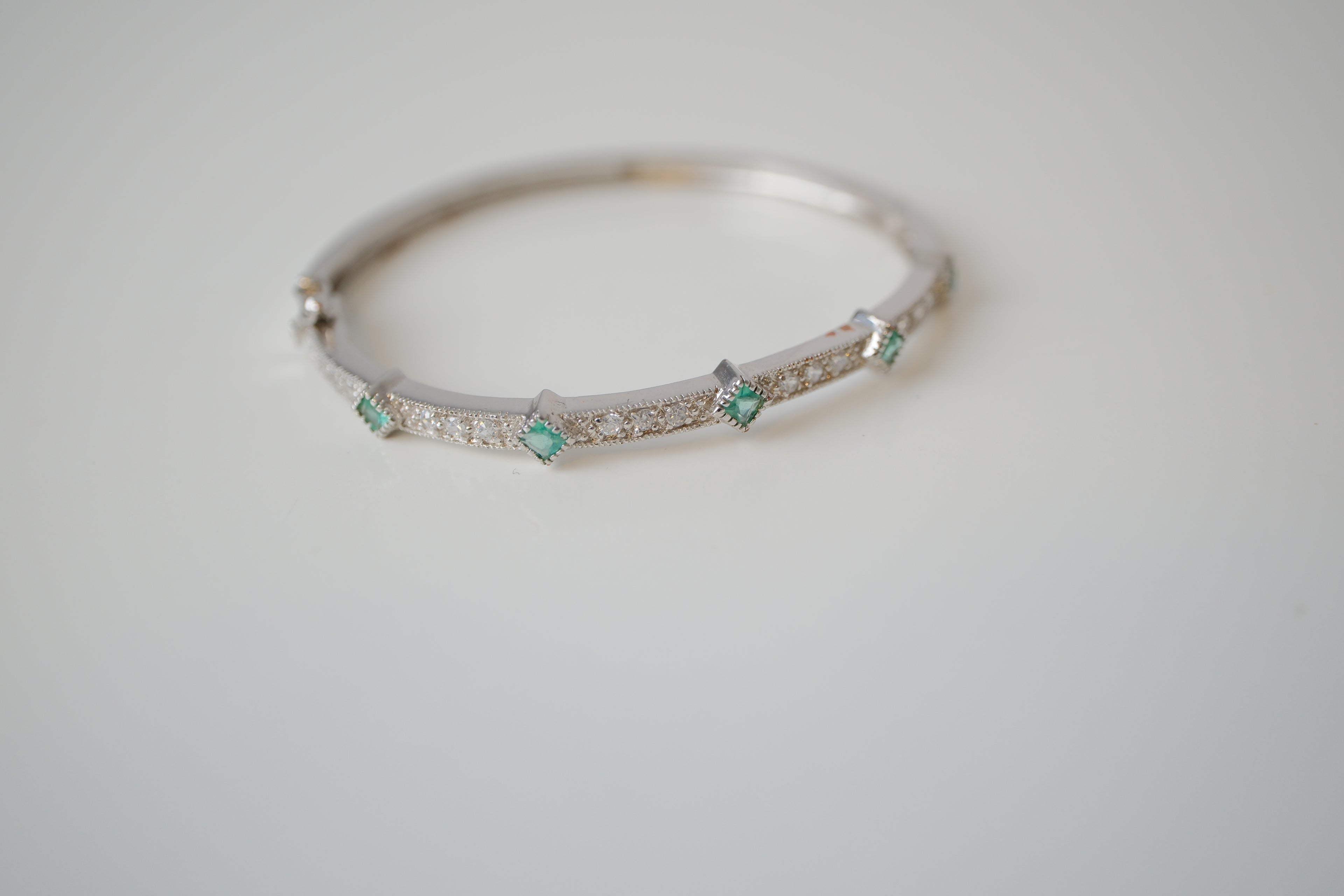 Silver tone bangle bracelet with white and green stones