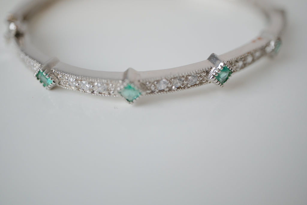 Silver tone bangle bracelet with white and green stones