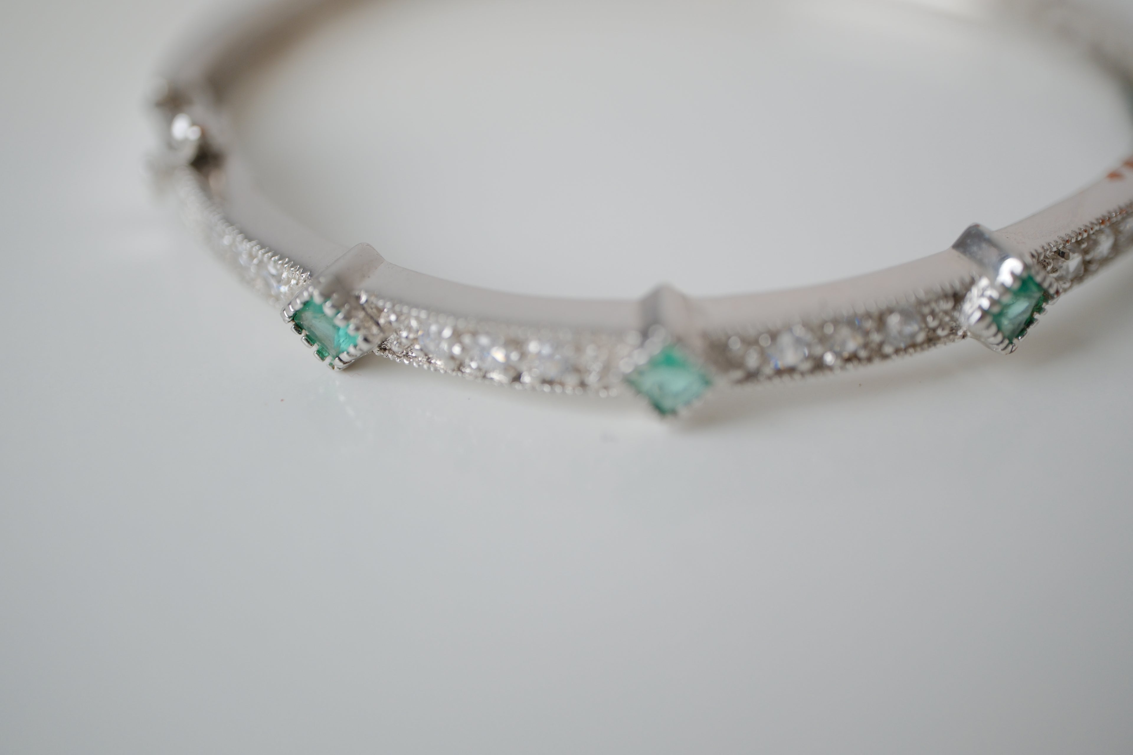 Silver tone bangle bracelet with white and green stones