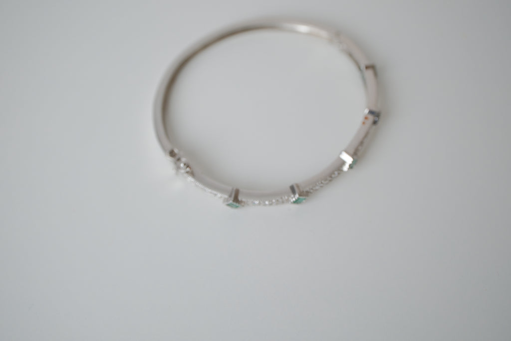 Silver tone bangle bracelet with white and green stones