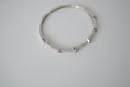 Silver tone bangle bracelet with white and green stones