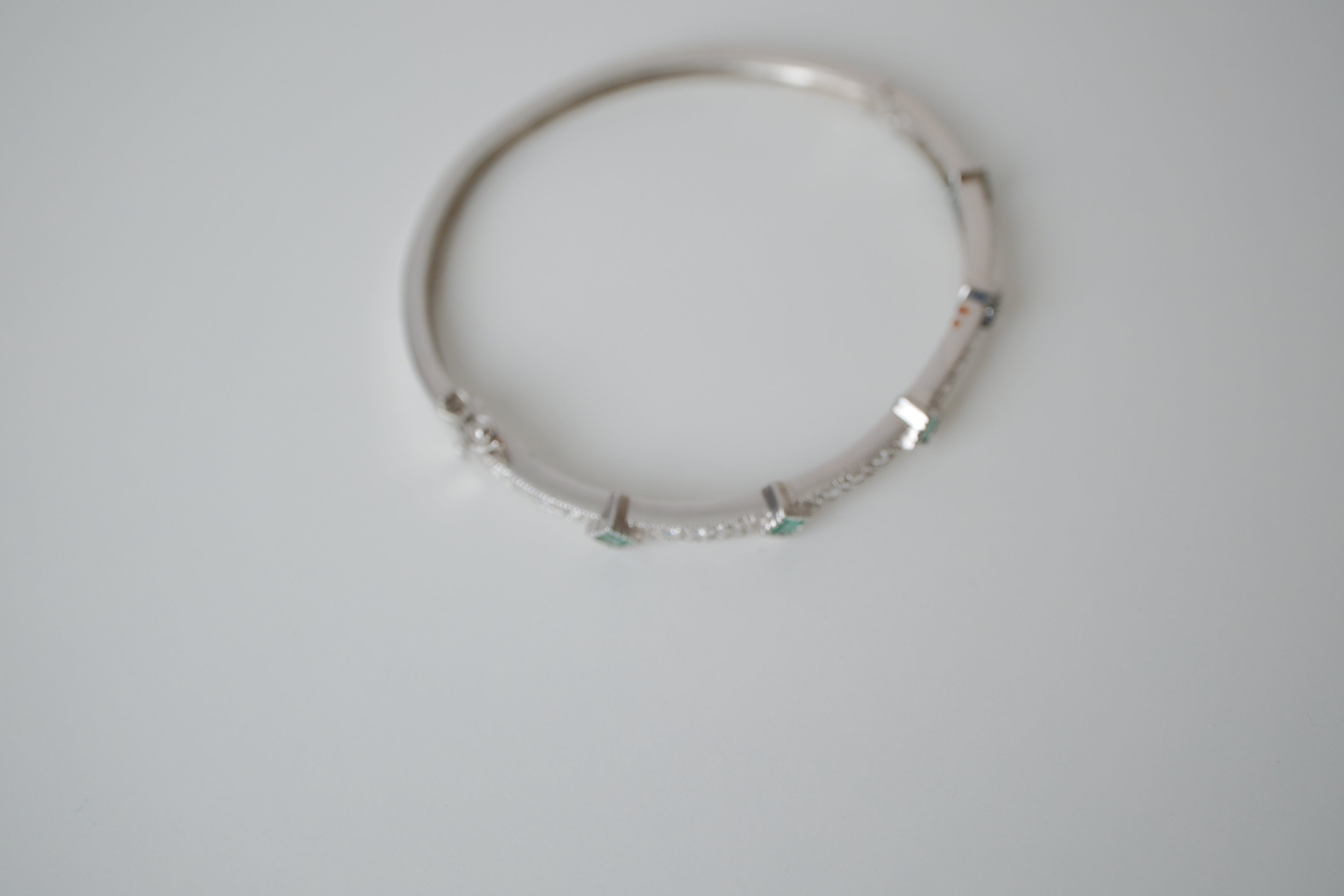 Silver tone bangle bracelet with white and green stones