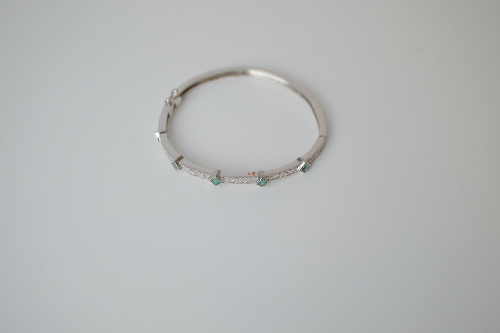 Silver tone bangle bracelet with white and green stones