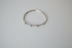 Silver tone bangle bracelet with white and green stones
