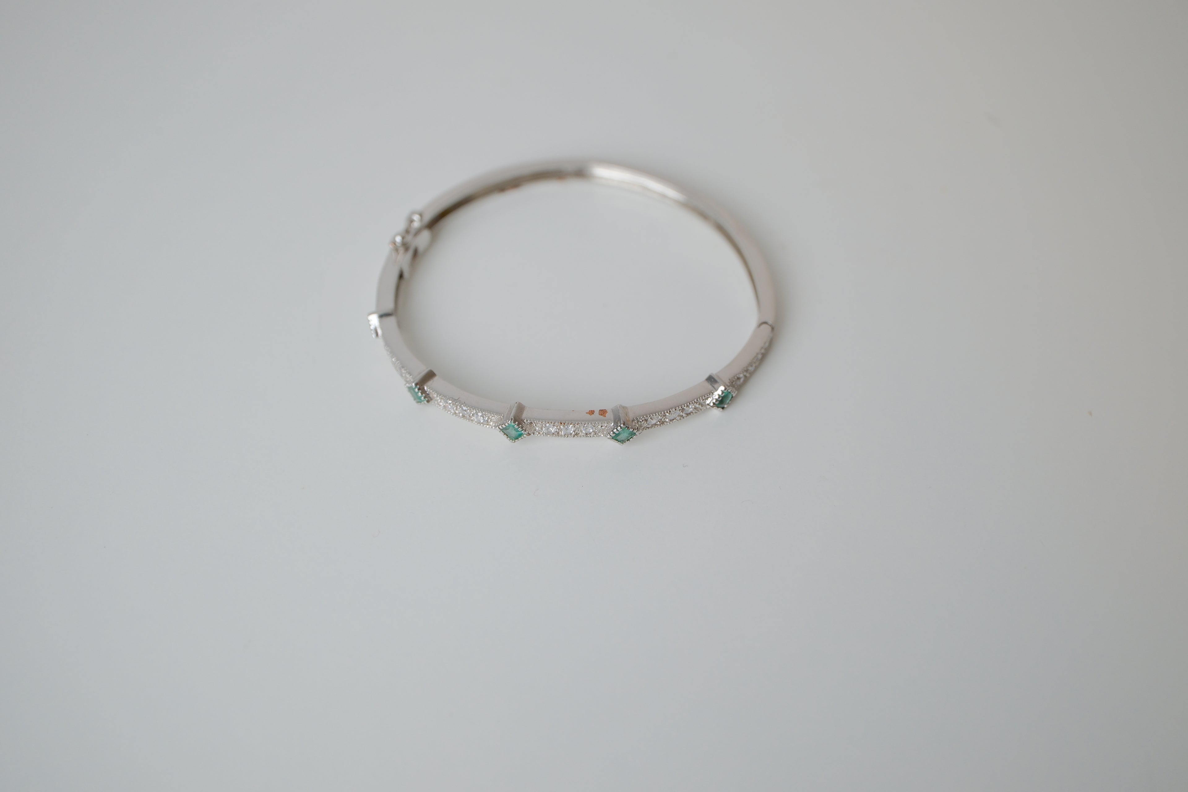 Silver tone bangle bracelet with white and green stones