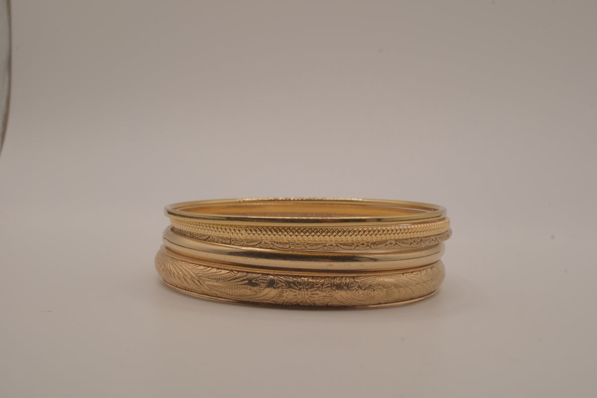 Set of 5 stacked gold bangle bracelets with intricate details