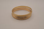 Set of 5 stacked gold bangle bracelets with intricate details