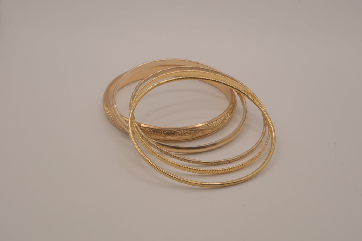 Set of 5 stacked gold bangle bracelets with intricate details