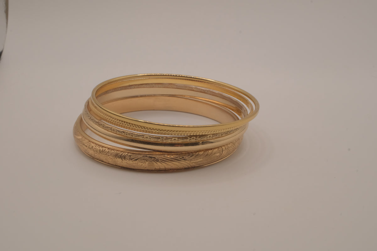 Set of 5 stacked gold bangle bracelets with intricate details